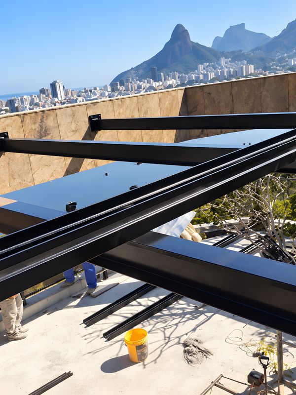 Estrutura de aço sendo montada na laje de um prédio, com o Morro Dois Irmãos ao fundo