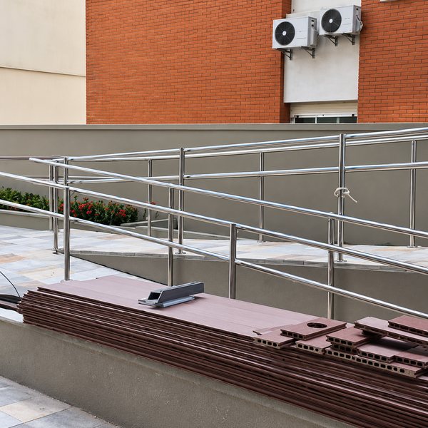 Guarda-corpo de aço inox ao longo de uma rampa de acesso, em prédio residencial