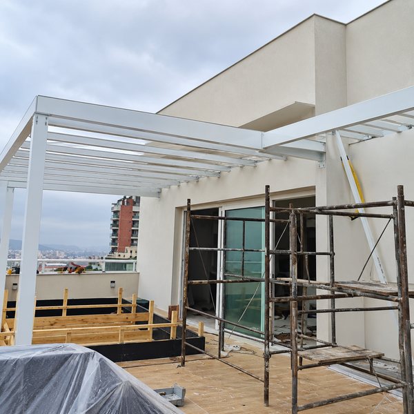Estrutura de cobertura branca sendo montada em terraço, com andaime
